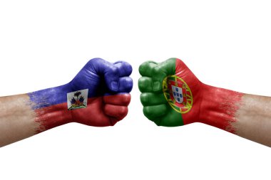 Two hands punch to each others on white background. Country flags painted fists, conflict crisis concept between haiti and portugal