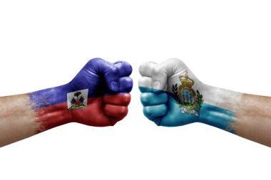 Two hands punch to each others on white background. Country flags painted fists, conflict crisis concept between haiti and san marino