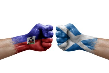 Two hands punch to each others on white background. Country flags painted fists, conflict crisis concept between haiti and scotland