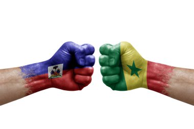 Two hands punch to each others on white background. Country flags painted fists, conflict crisis concept between haiti and senegal