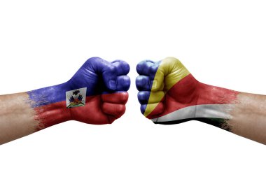 Two hands punch to each others on white background. Country flags painted fists, conflict crisis concept between haiti and seychelles