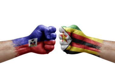 Two hands punch to each others on white background. Country flags painted fists, conflict crisis concept between haiti and zimbabwe