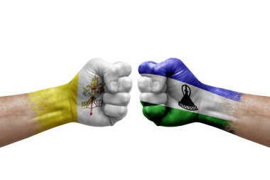 Two hands punch to each others on white background. Country flags painted fists, conflict crisis concept between holy see and lesotho