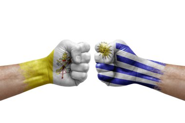 Two hands punch to each others on white background. Country flags painted fists, conflict crisis concept between holy see and uruguay