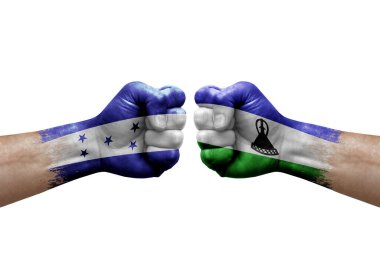 Two hands punch to each others on white background. Country flags painted fists, conflict crisis concept between honduras and lesotho