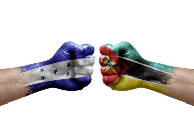 Two hands punch to each others on white background. Country flags painted fists, conflict crisis concept between honduras and mozambique