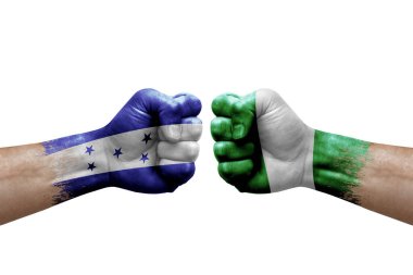 Two hands punch to each others on white background. Country flags painted fists, conflict crisis concept between honduras and nigeria