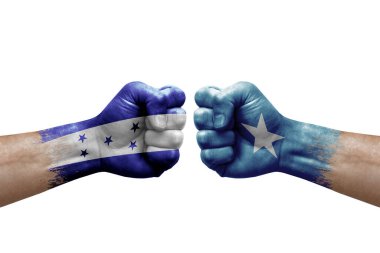 Two hands punch to each others on white background. Country flags painted fists, conflict crisis concept between honduras and somalia