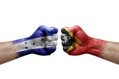 Two hands punch to each others on white background. Country flags painted fists, conflict crisis concept between honduras and timor leste