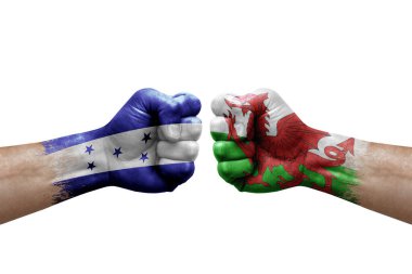 Two hands punch to each others on white background. Country flags painted fists, conflict crisis concept between honduras and wales