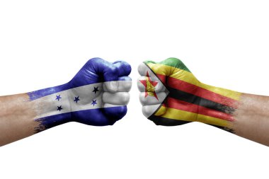 Two hands punch to each others on white background. Country flags painted fists, conflict crisis concept between honduras and zimbabwe