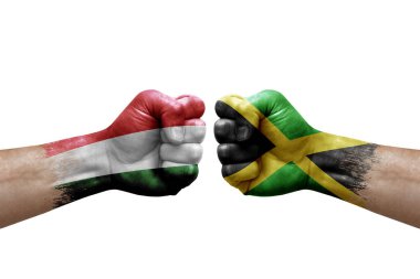 Two hands punch to each others on white background. Country flags painted fists, conflict crisis concept between hungary and jamaica