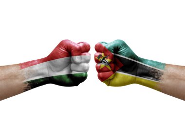 Two hands punch to each others on white background. Country flags painted fists, conflict crisis concept between hungary and mozambique