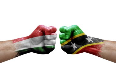 Two hands punch to each others on white background. Country flags painted fists, conflict crisis concept between hungary and saint kitts and nevis