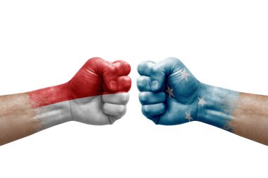Two hands punch to each others on white background. Country flags painted fists, conflict crisis concept between indonesia and micronesia