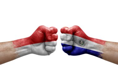 Two hands punch to each others on white background. Country flags painted fists, conflict crisis concept between indonesia and paraguay