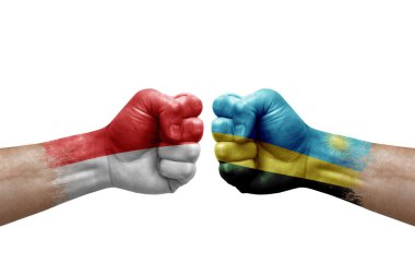 Two hands punch to each others on white background. Country flags painted fists, conflict crisis concept between indonesia and rwanda