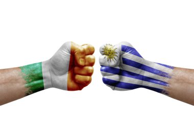 Two hands punch to each others on white background. Country flags painted fists, conflict crisis concept between ireland and uruguay