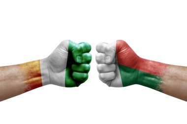 Two hands punch to each others on white background. Country flags painted fists, conflict crisis concept between ivory coast and madagascar