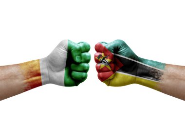 Two hands punch to each others on white background. Country flags painted fists, conflict crisis concept between ivory coast and mozambique