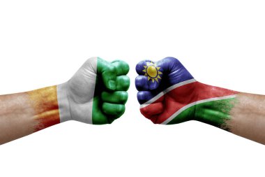 Two hands punch to each others on white background. Country flags painted fists, conflict crisis concept between ivory coast and namibia