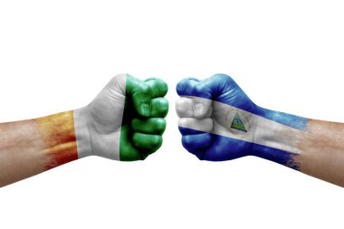 Two hands punch to each others on white background. Country flags painted fists, conflict crisis concept between ivory coast and nicaragua