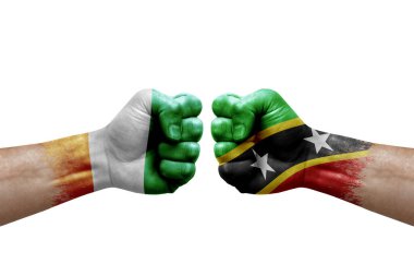 Two hands punch to each others on white background. Country flags painted fists, conflict crisis concept between ivory coast and saint kitts and nevis