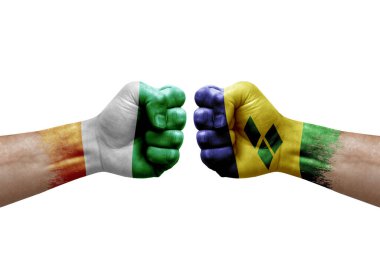 Two hands punch to each others on white background. Country flags painted fists, conflict crisis concept between ivory coast and saint vincent and the grenadines