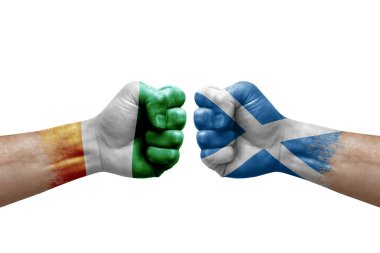 Two hands punch to each others on white background. Country flags painted fists, conflict crisis concept between ivory coast and scotland