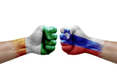 Two hands punch to each others on white background. Country flags painted fists, conflict crisis concept between ivory coast and slovenia
