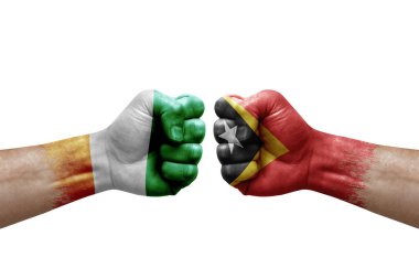 Two hands punch to each others on white background. Country flags painted fists, conflict crisis concept between ivory coast and timor leste