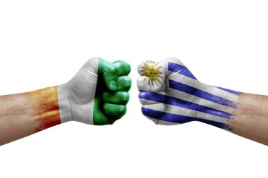 Two hands punch to each others on white background. Country flags painted fists, conflict crisis concept between ivory coast and uruguay
