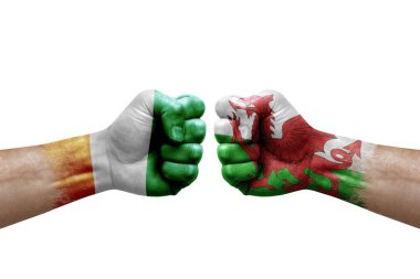 Two hands punch to each others on white background. Country flags painted fists, conflict crisis concept between ivory coast and wales