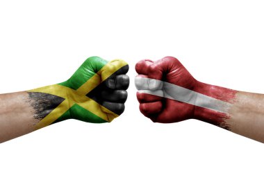 Two hands punch to each others on white background. Country flags painted fists, conflict crisis concept between jamaica and latvia