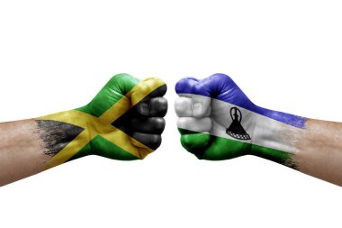 Two hands punch to each others on white background. Country flags painted fists, conflict crisis concept between jamaica and lesotho
