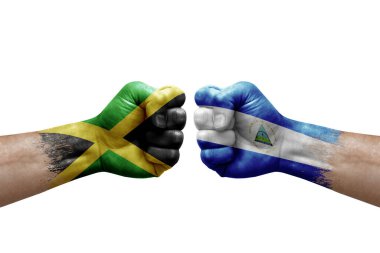 Two hands punch to each others on white background. Country flags painted fists, conflict crisis concept between jamaica and nicaragua