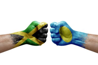 Two hands punch to each others on white background. Country flags painted fists, conflict crisis concept between jamaica and palau