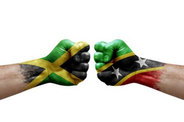 Two hands punch to each others on white background. Country flags painted fists, conflict crisis concept between jamaica and saint kitts and nevis