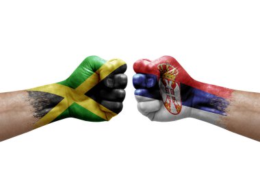 Two hands punch to each others on white background. Country flags painted fists, conflict crisis concept between jamaica and serbia