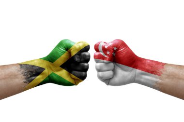 Two hands punch to each others on white background. Country flags painted fists, conflict crisis concept between jamaica and singapore