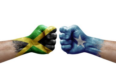 Two hands punch to each others on white background. Country flags painted fists, conflict crisis concept between jamaica and somalia