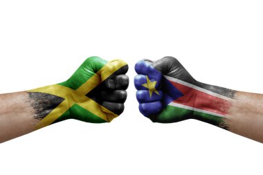 Two hands punch to each others on white background. Country flags painted fists, conflict crisis concept between jamaica and south sudan