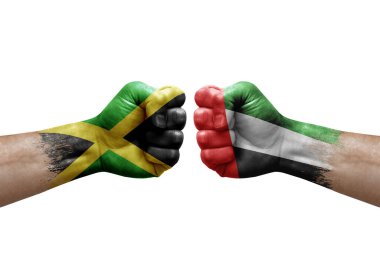 Two hands punch to each others on white background. Country flags painted fists, conflict crisis concept between jamaica and united arab emirates