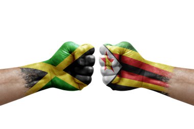 Two hands punch to each others on white background. Country flags painted fists, conflict crisis concept between jamaica and zimbabwe