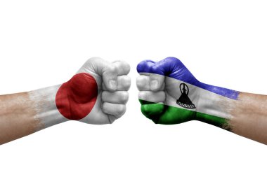 Two hands punch to each others on white background. Country flags painted fists, conflict crisis concept between japan and lesotho