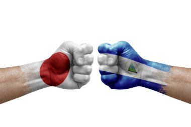 Two hands punch to each others on white background. Country flags painted fists, conflict crisis concept between japan and nicaragua
