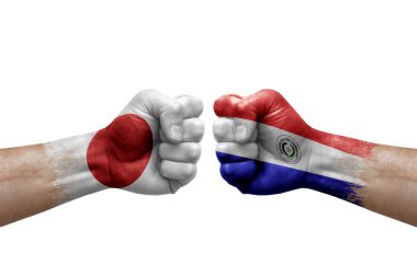 Two hands punch to each others on white background. Country flags painted fists, conflict crisis concept between japan and paraguay