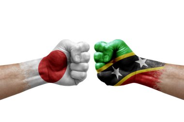 Two hands punch to each others on white background. Country flags painted fists, conflict crisis concept between japan and saint kitts and nevis