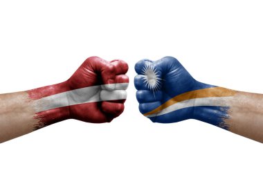 Two hands punch to each others on white background. Country flags painted fists, conflict crisis concept between latvia and marshall islands