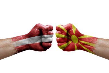 Two hands punch to each others on white background. Country flags painted fists, conflict crisis concept between latvia and north macedonia